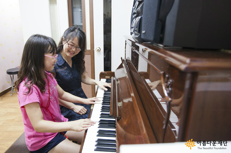 김서연 원장과 아이가 즐거운 표정으로 피아노를 연주하고 있다.